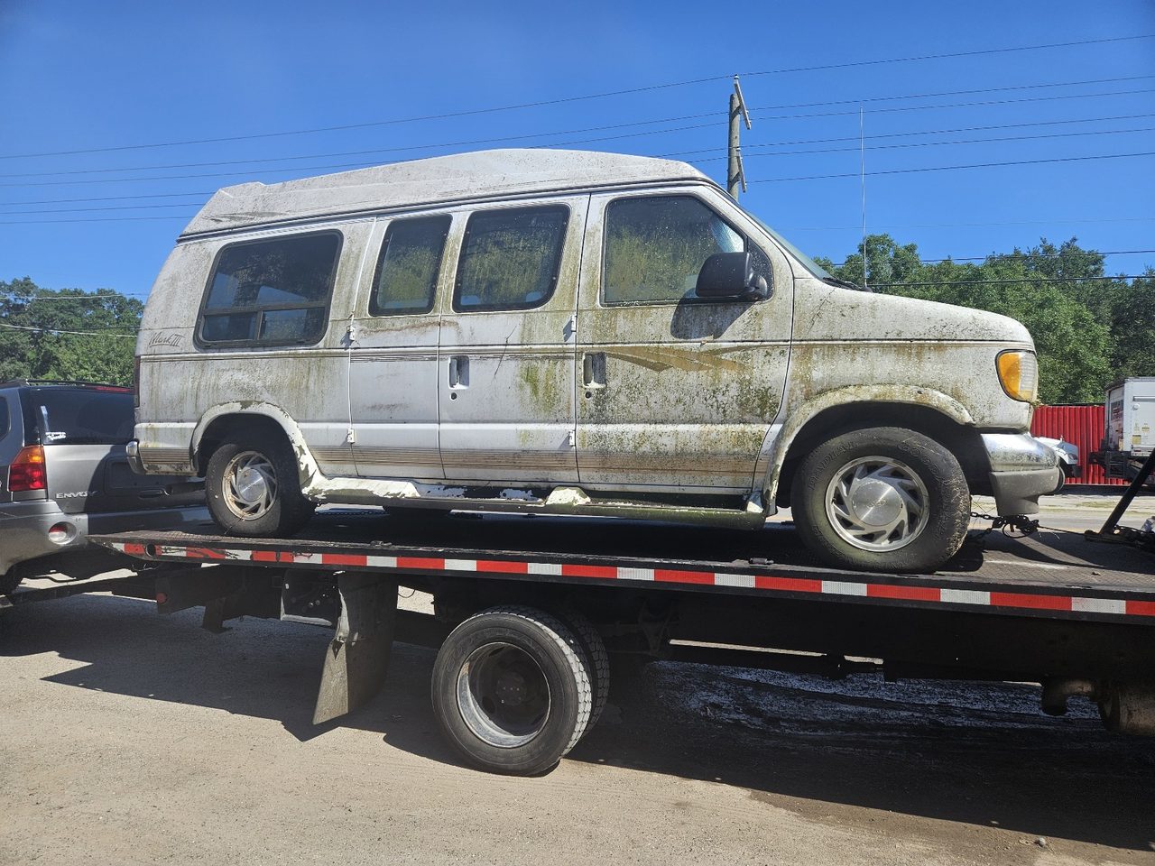 Flatbed tow truck hauling a white cargo van away for free