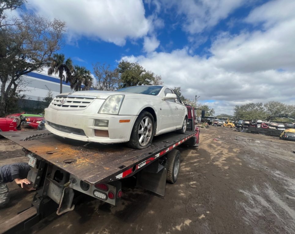Flatbed tow truck hauling a damaged Chrysler 300 junk car in Tampa Bay