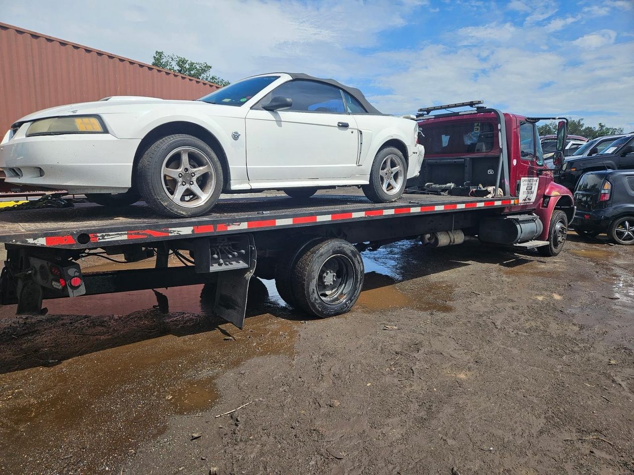 Flatbed tow truck hauling a Mercedes-Benz convertible junk car