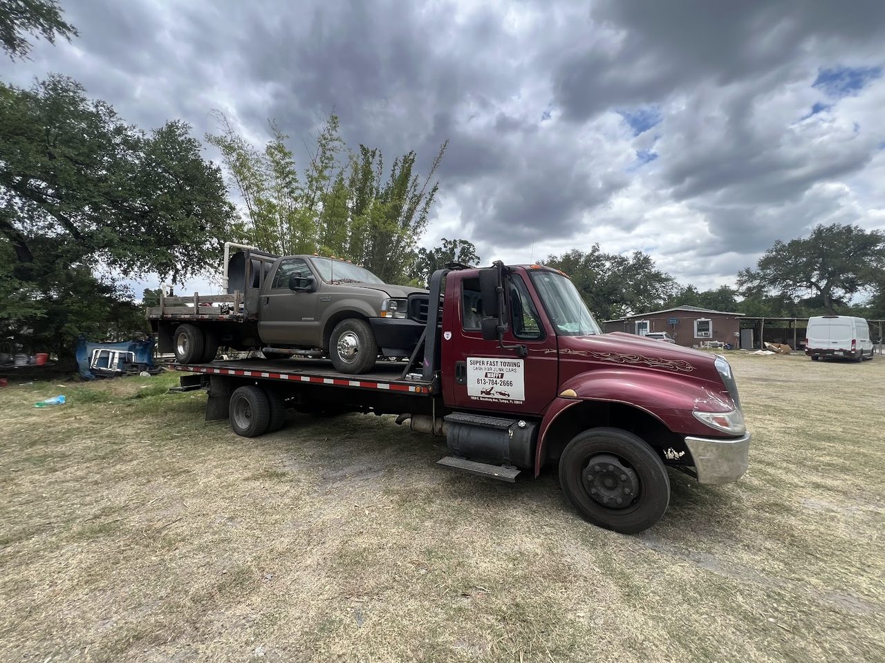 Flatbed truck picking up an old pickup in a rural Tampa Bay area
