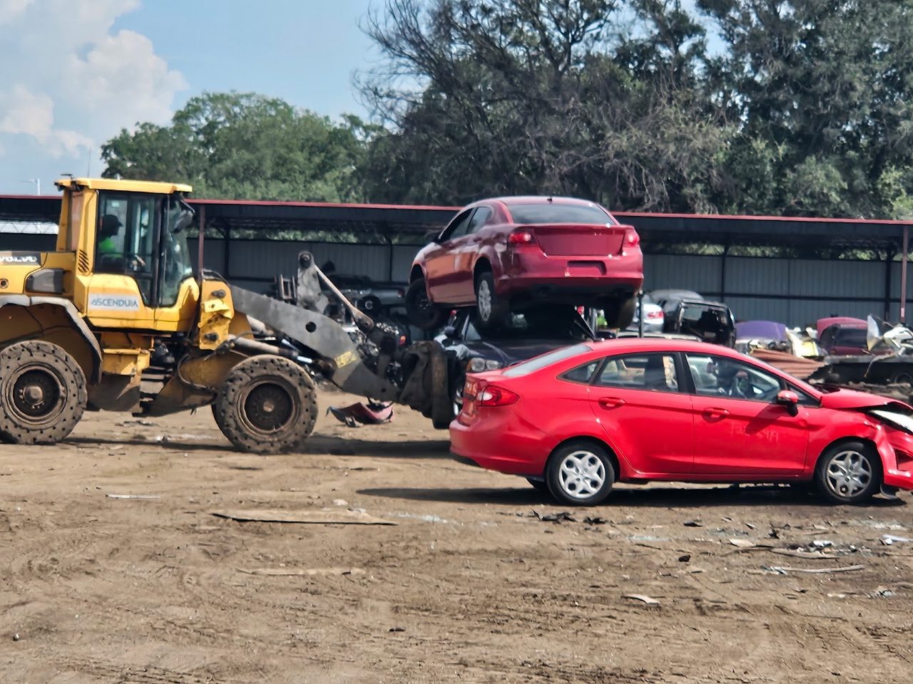 Front-end loader stacking end-of-life vehicles at the salvage yard