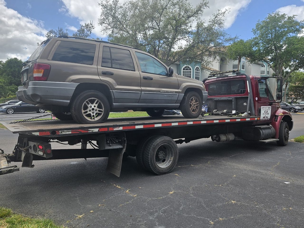 Rollback tow truck hauling a Jeep Grand Cherokee for cash