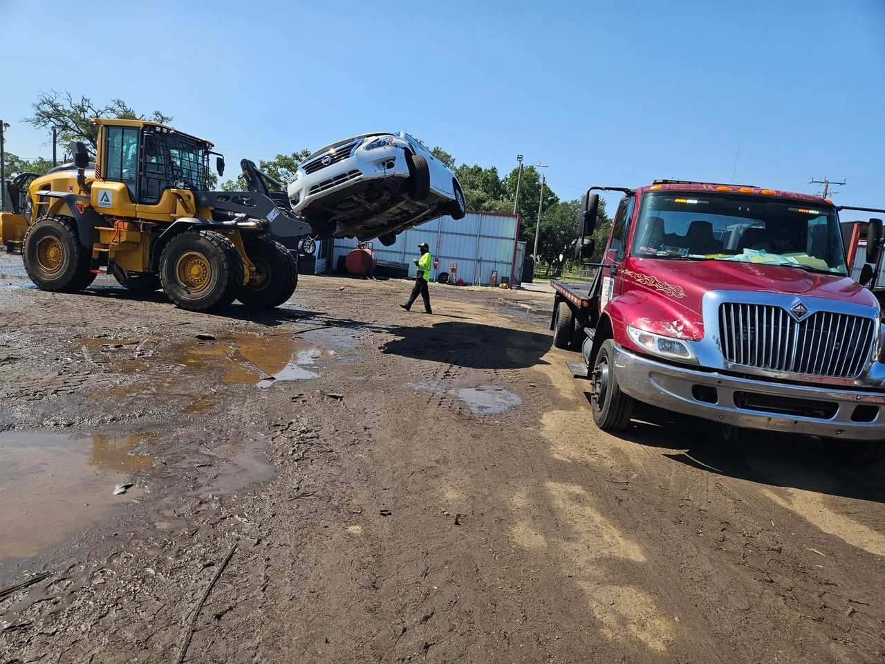 Loader lifting a vehicle onto a truck at our Florida salvage yard